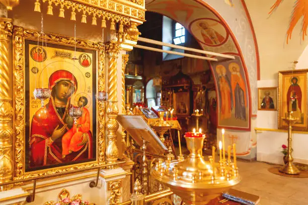 Interior of Orthodox church. Symbolic Orthodox gold cross with the crucifixion of Jesus, golden candleholders and other details.