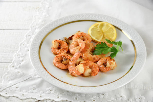 istock fried tiger prawns, marinated with garlic, spices, herbs and lemon on a fine white plate, italian parsley garnish, copy space on the bright background 696535396