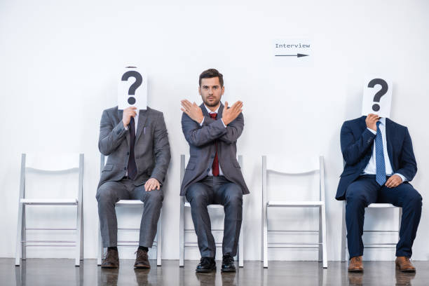 istock businesspeople sitting in queue and waiting for interview, holding question marks in office, business concept 696535714