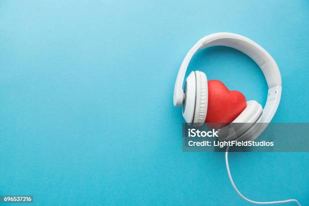 White Headphones With Red Heart Sign In The Middle On Blue Surface Stock Photo - Download Image Now