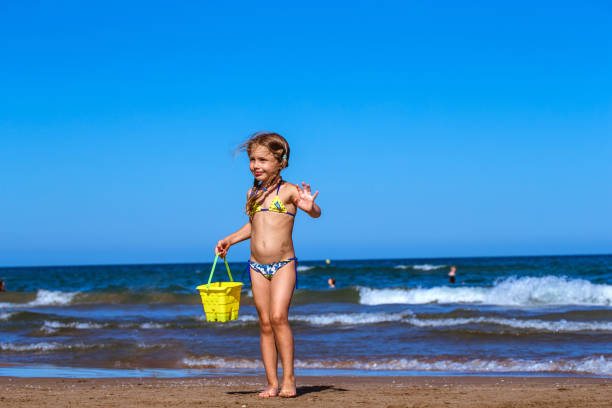 Two happy smiling boys run with water buckets from sea waves on sand beach during summer vacations