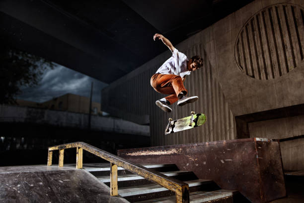 skater saltando sobre su skate en el skatepark - stunt fotografías e imágenes de stock