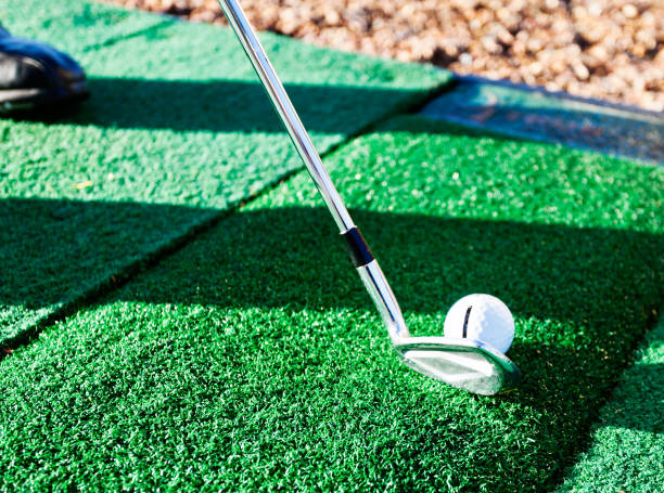 Golf club and ball on artificial turf at driving range An unseen person holds a golf club, about to hit the ball, on artificial grass at a practice driving range. artifical grass stock pictures, royalty-free photos & images