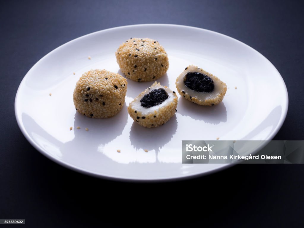 Japanese sesame mochi on black background Japanese sesame mochi (sticky rice cakes) on white plate isolated on black background Asia Stock Photo