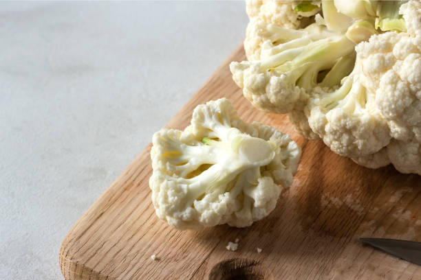 istock Raw cauliflower cut into slices on wooden cutting board. 696554496
