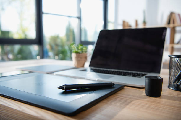 istock laptop with blank screen and graphics tablet on wooden tabletop at office 696556702