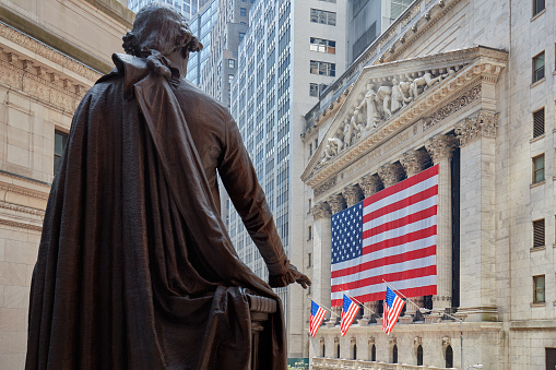 New York - September 8, 2016: Wall Street Stock Exchange building with big US flag and George Washington statue back, financial district in New York in a sunny day. Also known as Big Board is the largest stock exchange in the world by capitalization.