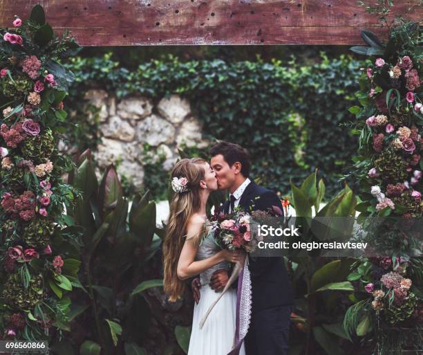 Amazing Wedding Ceremony With A Lot Of Fresh Flowers In Rustic Style Happy Newlyweds Kissing Stock Photo - Download Image Now