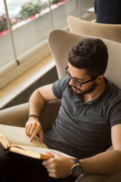 istock Young man reading a book in a cafe 696561452