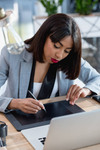 istock young african american designer working with drawing tablet and laptop at office 696564476
