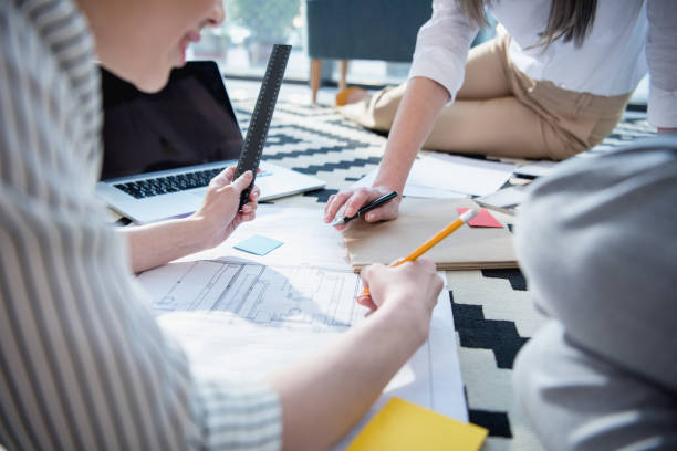 istock cropped shot of architects working with blueprints and laptop at office 696565342