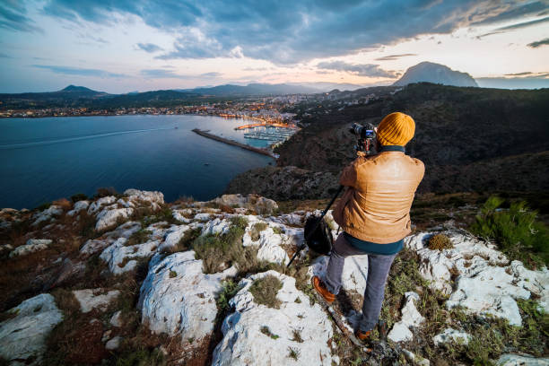 istock Young attractive photographer making photos with camera on tripod at sunset 696571054