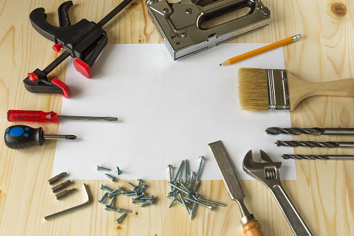 Tools for repairs in the house on a wooden table. Screws, screwdrivers, clamps