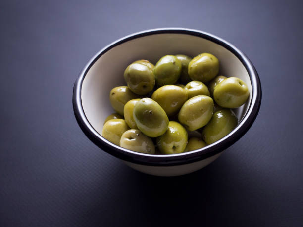 istock Green olives in bowl isolated on black 696585350