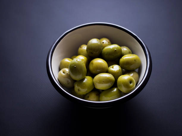 istock Green olives in bowl isolated on black 696585362