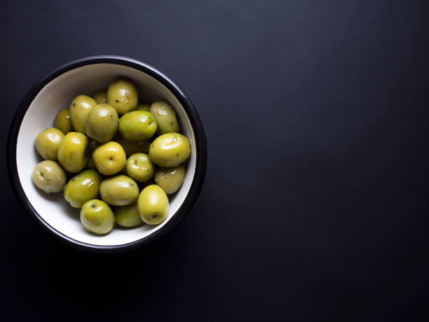 istock Green olives in bowl isolated on black 696585368