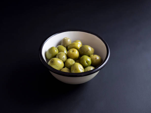 istock Green olives in bowl isolated on black 696585384