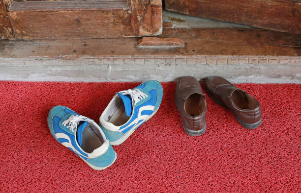 istock Sneakers and leather shoes on doormat. 696588856