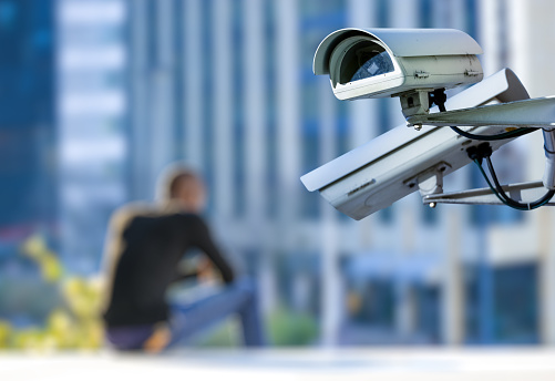 security CCTV camera or surveillance system with young man on blurry background