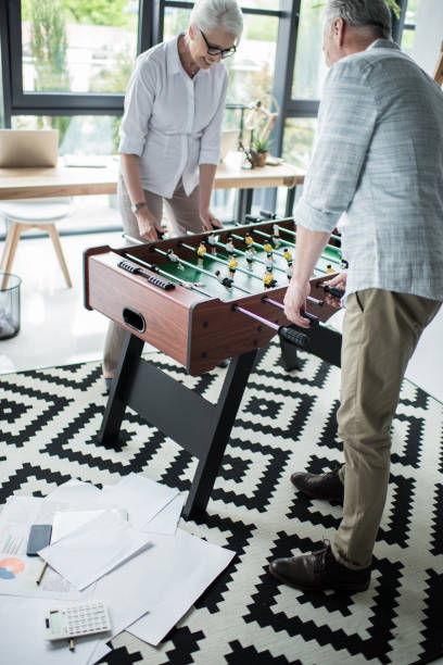 istock Senior business colleagues playing foosball at office 696597244