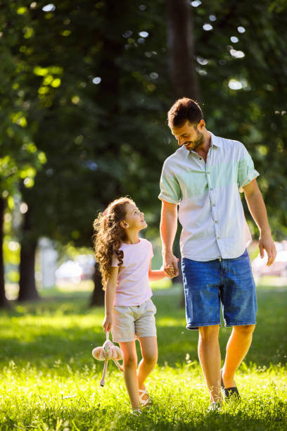 Father and daughter taking a walk, holding hands stock photo