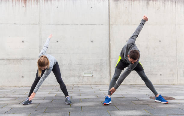 close up of couple stretching on city street fitness, sport, exercising, training and people concept - close up of couple stretching on city street warming up stock pictures, royalty-free photos & images