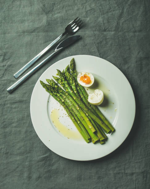 istock Cooked asparagus with soft-boiled egg and herbs on white plate 696612942