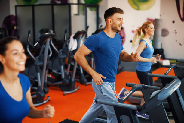 istock Young man and two women warming up on treadmill at gym 696613256