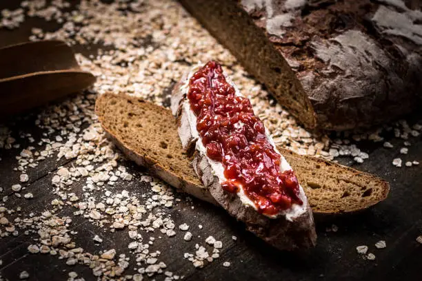 Fruity Jam on Traditional Whole Grain Rye Bread on Dark Wooden Table Background