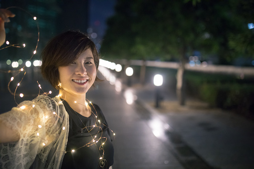 Young woman playing with light cable in urban city at night