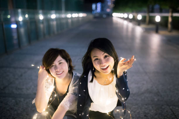 Happy young business women playing with lights after work