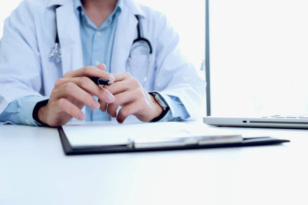 istock Doctor working with laptop computer and writing on paperwork. Hospital background. 696640372