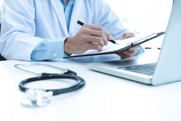 istock Doctor working with laptop computer and writing on paperwork. Hospital background. 696640384