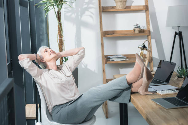 istock Senior business woman relaxing with her legs on table 696646820