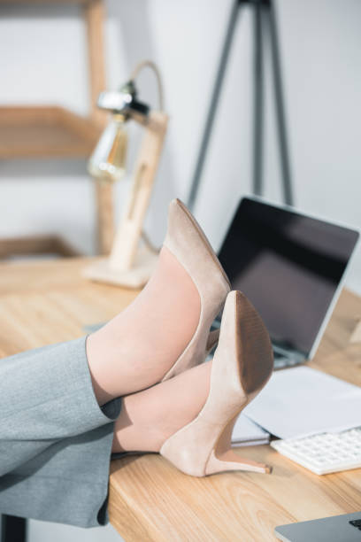 istock womens legs in stilettos on table in office 696647688
