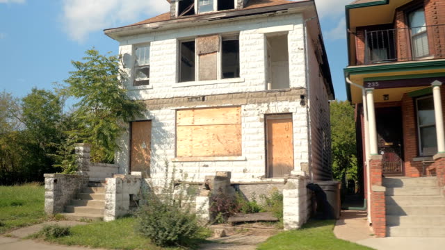 CLOSE UP Derelict decaying home next to beautiful semi-detached house in Detroit
