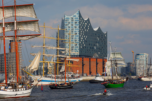 Hamburg, Germany - May 07, 2017: Hamburg harbor birthday (Hafengeburtstag) celebration ship parade. Several tall ships crossing the Elbe river in front of the Elbphiharmonie concert hall. People on boats and the visitors platform enjoy the parade.