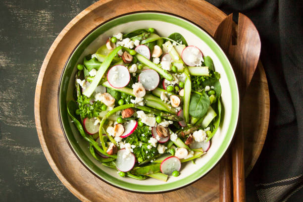 istock Spring vegetable salad with asparagus, zucchini, radish, spinach and goat cheese on dark background. 696669790