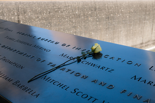 New York, USA - Oct 9th, 2016: A single yellow rose placed on the reflecting pool memorial at Ground Zero in lower Manhattan late in the day.