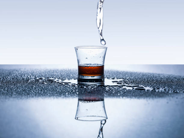 スプラッシュの上部から出てくる水を飲んでのガラス。 - overflowing water glass bottle ストックフォトと画像