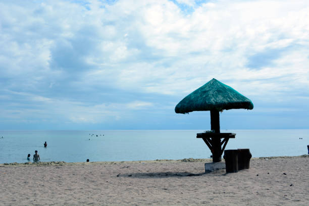 Laiya, San Juan, Batangas, Philippines - May 28, 2017: Palm leaves Parasol on white sand beach under cloudy blue sky