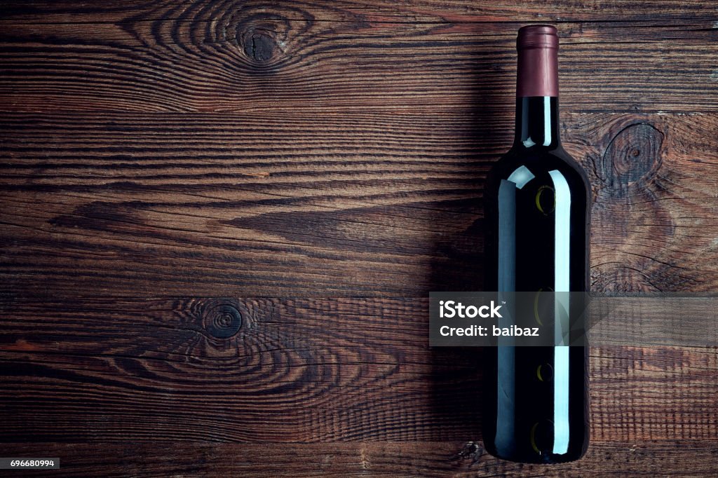 Bottle of red wine Bottle of red wine on dark wooden background from top view Bottle Stock Photo