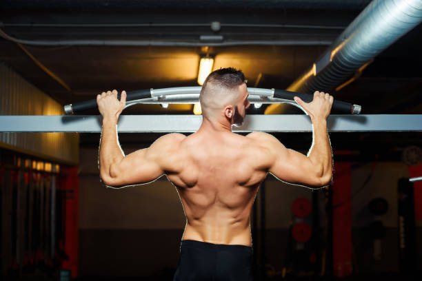 istock Athlete muscular fit man pulling up on horizontal bar in a gym 696681160