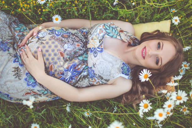 Beautiful pregnant woman lying in the camomile field stock photo