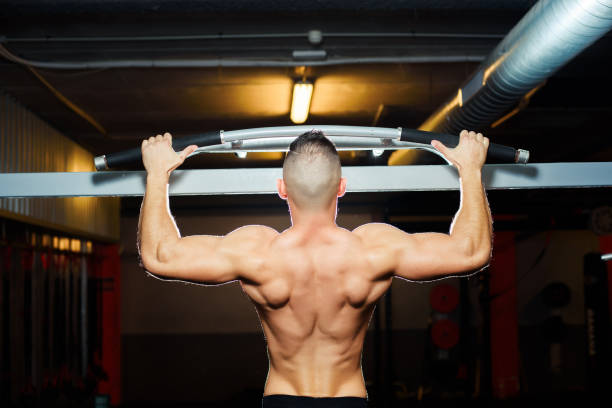 istock Athlete muscular fit man pulling up on horizontal bar in a gym 696693640