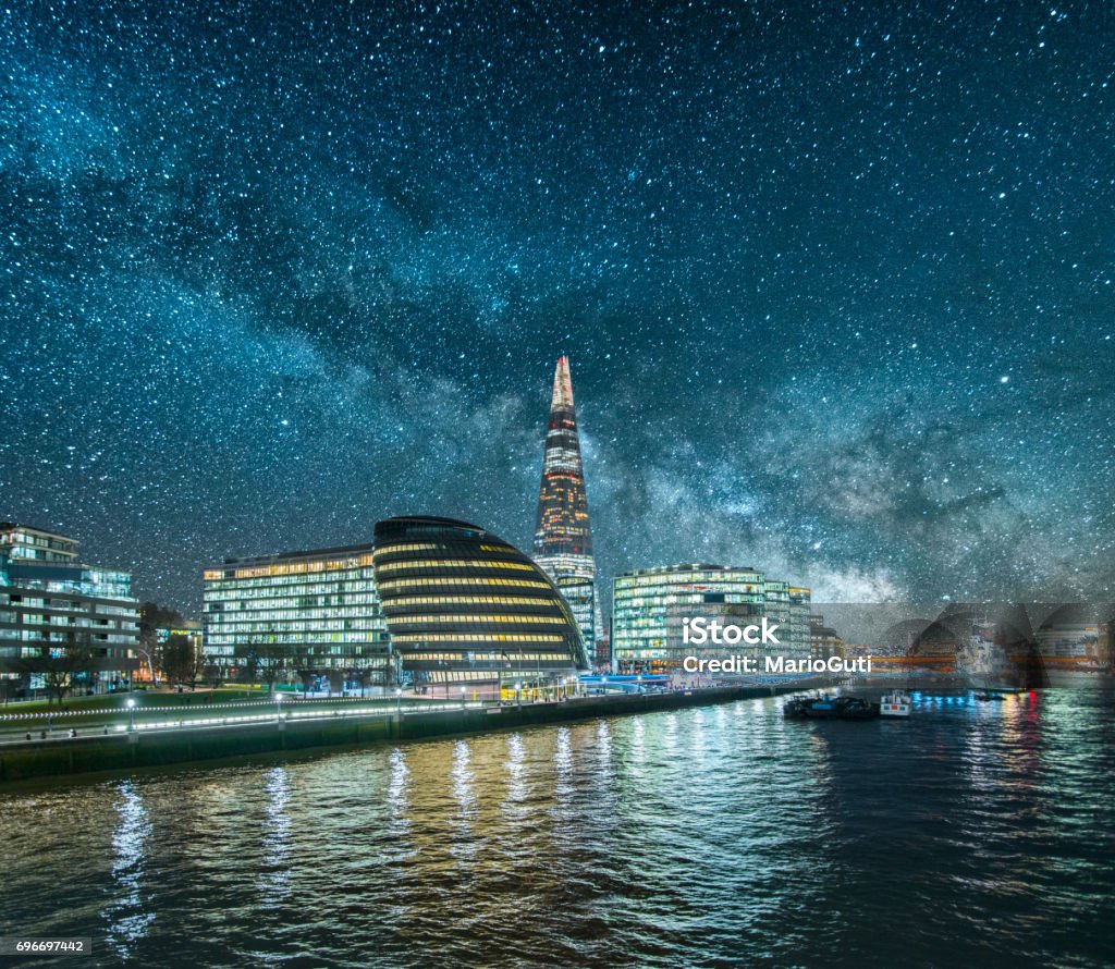 London at night A beautiful image featuring skyscrapers in London and their reflection on the thames river under the milky way Night Stock Photo