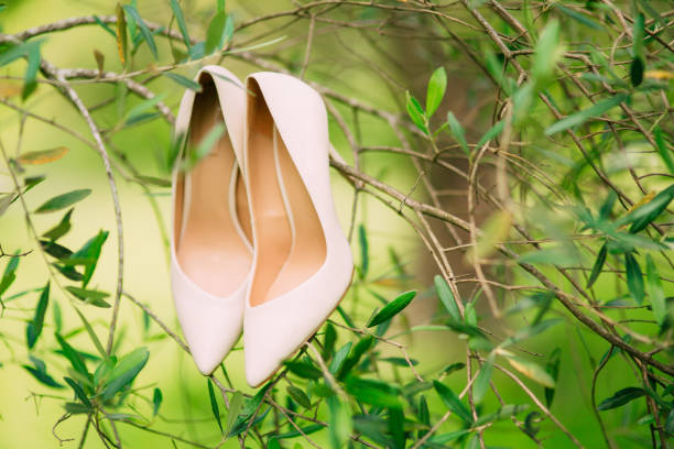 istock Light cream bride shoes hanging on a branch 696704758