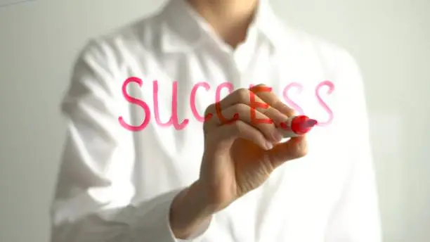Photo of Woman writing Success on transparent screen. Businesswoman write on board