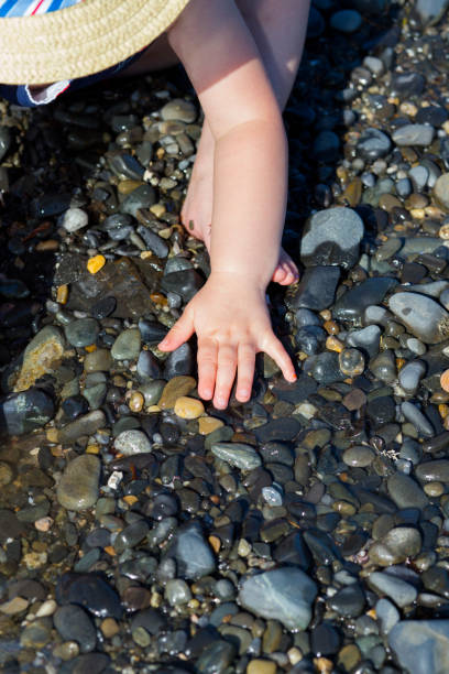Close-up portrait of a toddler girl enjoying the beach and playing with rocks.
