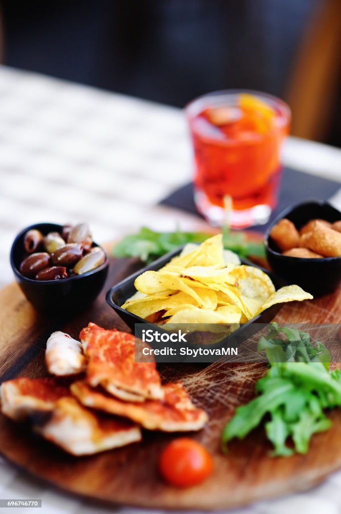 Glass of cocktail (sparkling wine with Aperol) and appetizer platter Italian aperitives/aperitif: glass of cocktail (sparkling wine with Aperol) and appetizer platter on the table Appetizer Stock Photo